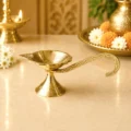 Premium brass handheld pooja diya with engraved long handle and traditional leaf-shaped oil lamp for Aarti, home temple and daily worship.