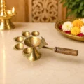 Premium brass Panch Aarti diya with five leaf-shaped oil lamps, central oil bowl and wooden handle for home temple, daily worship and religious ceremonies.