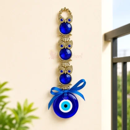 Premium blue evil eye owl wall hanging with glass nazar charm, blue crystal stones and antique gold finish for home entrance, office and vastu décor.